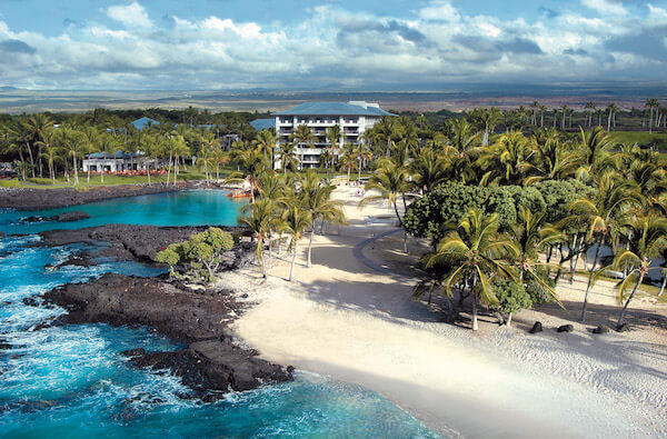 The Fairmont Orchard resort and Hawaii coastline complete with the ocean and palm tree-ridden shoreline.