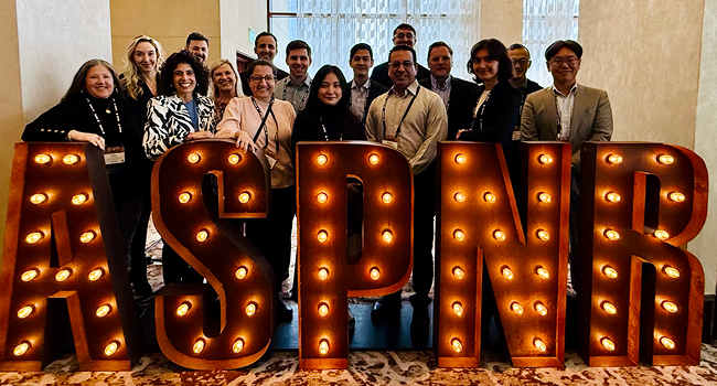 People posing behind a sign reading "ASPNR"