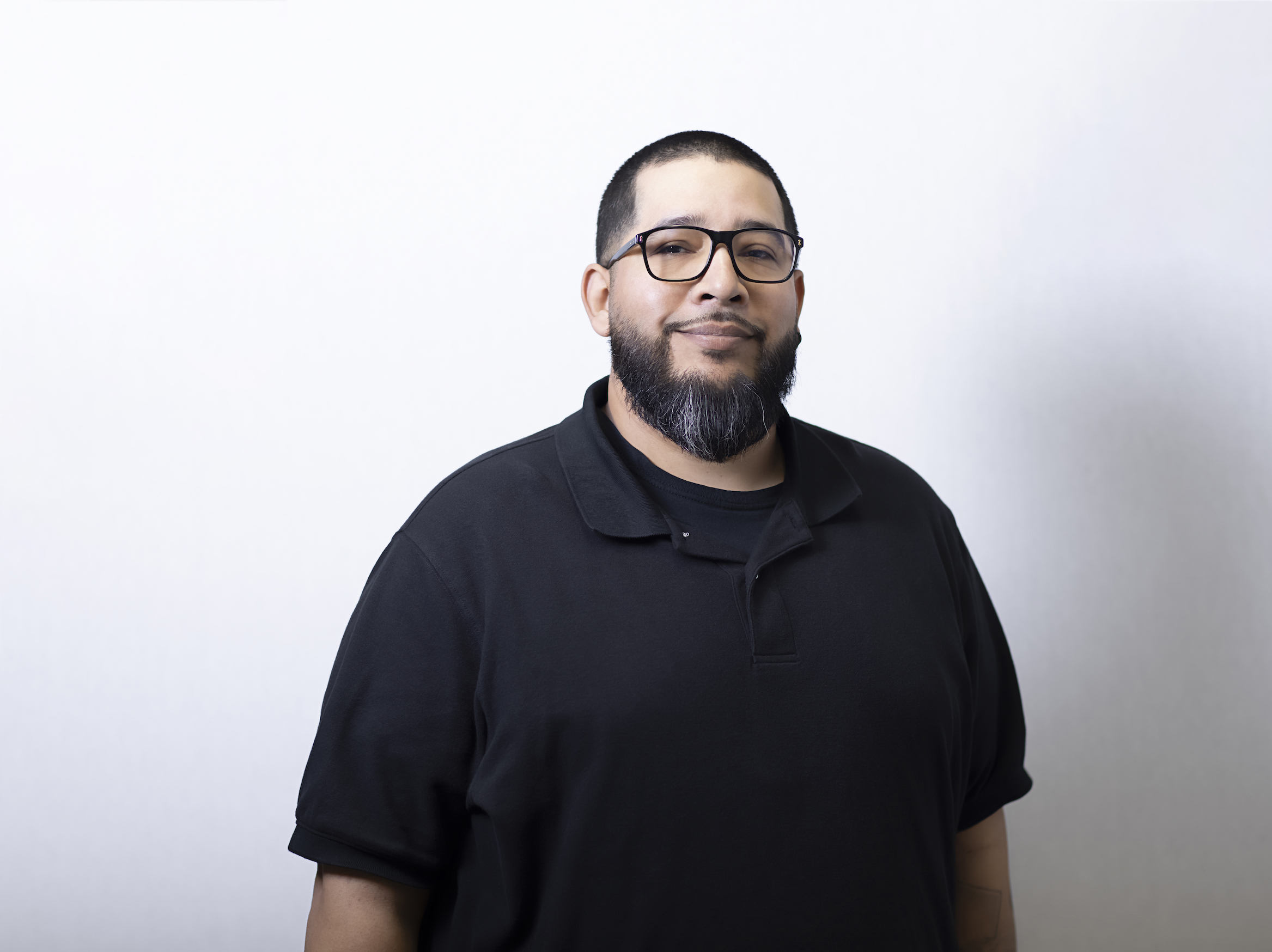 Rudy Baltodano leads UCSF Health's radiology scheduling team. Man in a black polo shirt smiling.
