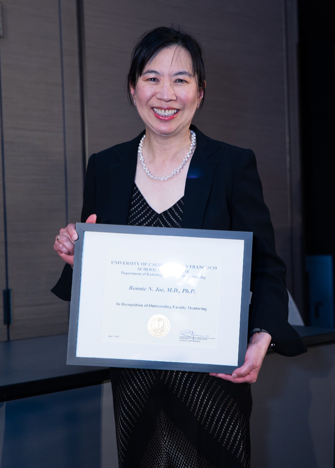 Bonnie Joe, MD, PhD, receives the 2024 Outstanding Faculty Mentoring Award at graduation. Woman holding an award.
