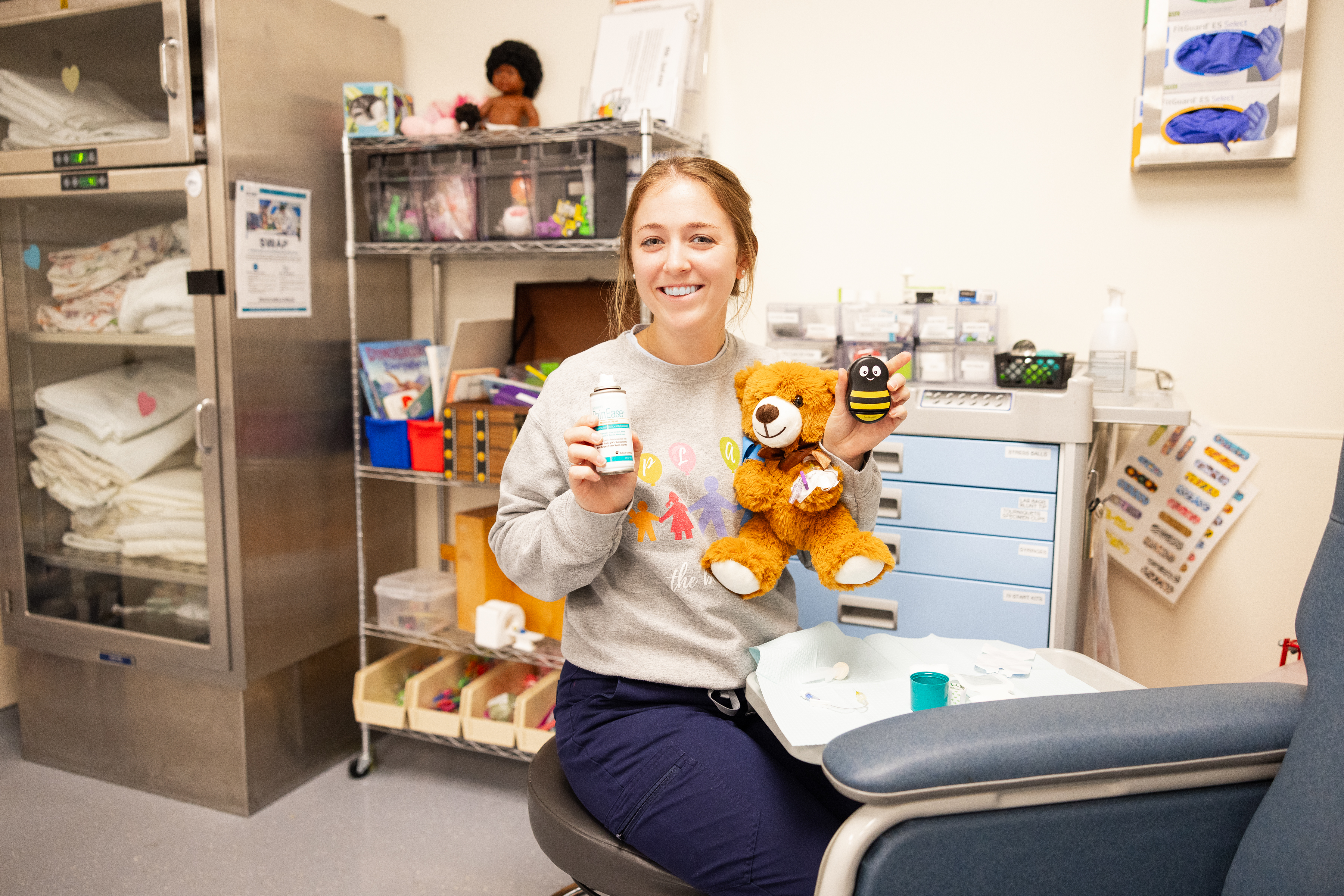 UCSF Health Child Life Specialist Emily Keis demonstrates a procedure on a teddy bear. Woman holding a teddy bear at UCSF Benioff Children's Hospital in Mission Bay.