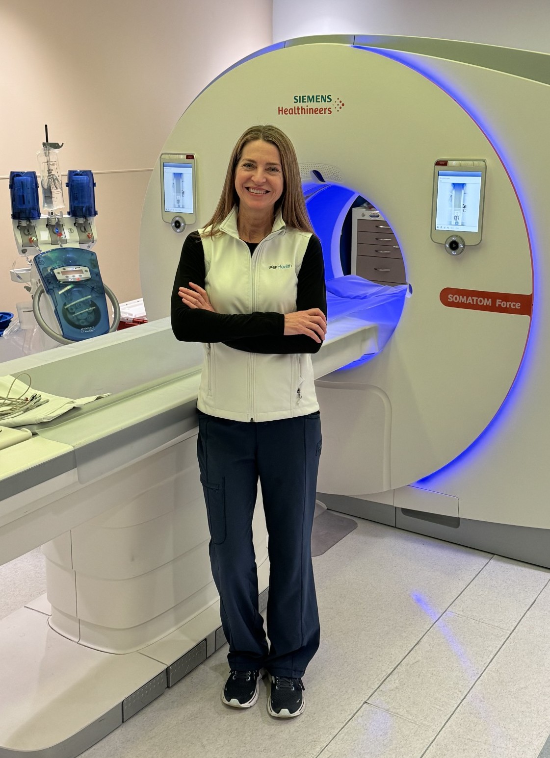 A woman smiling with her arms crossed on her chest.