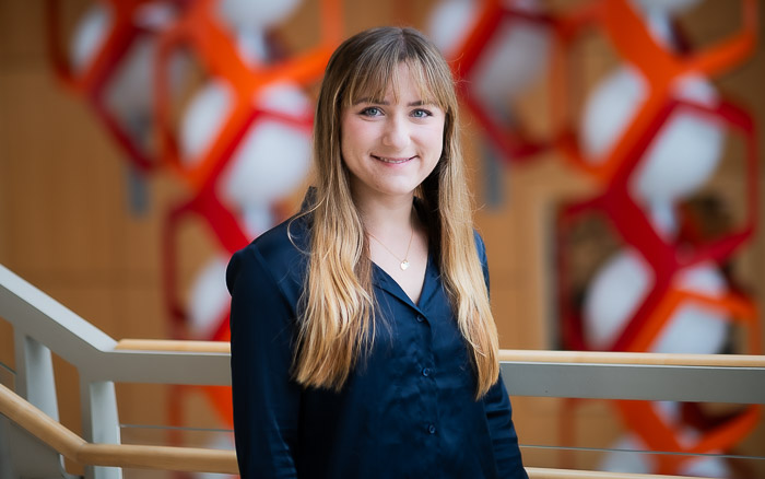 Woman with long hair and bangs stands in front of a sculpture