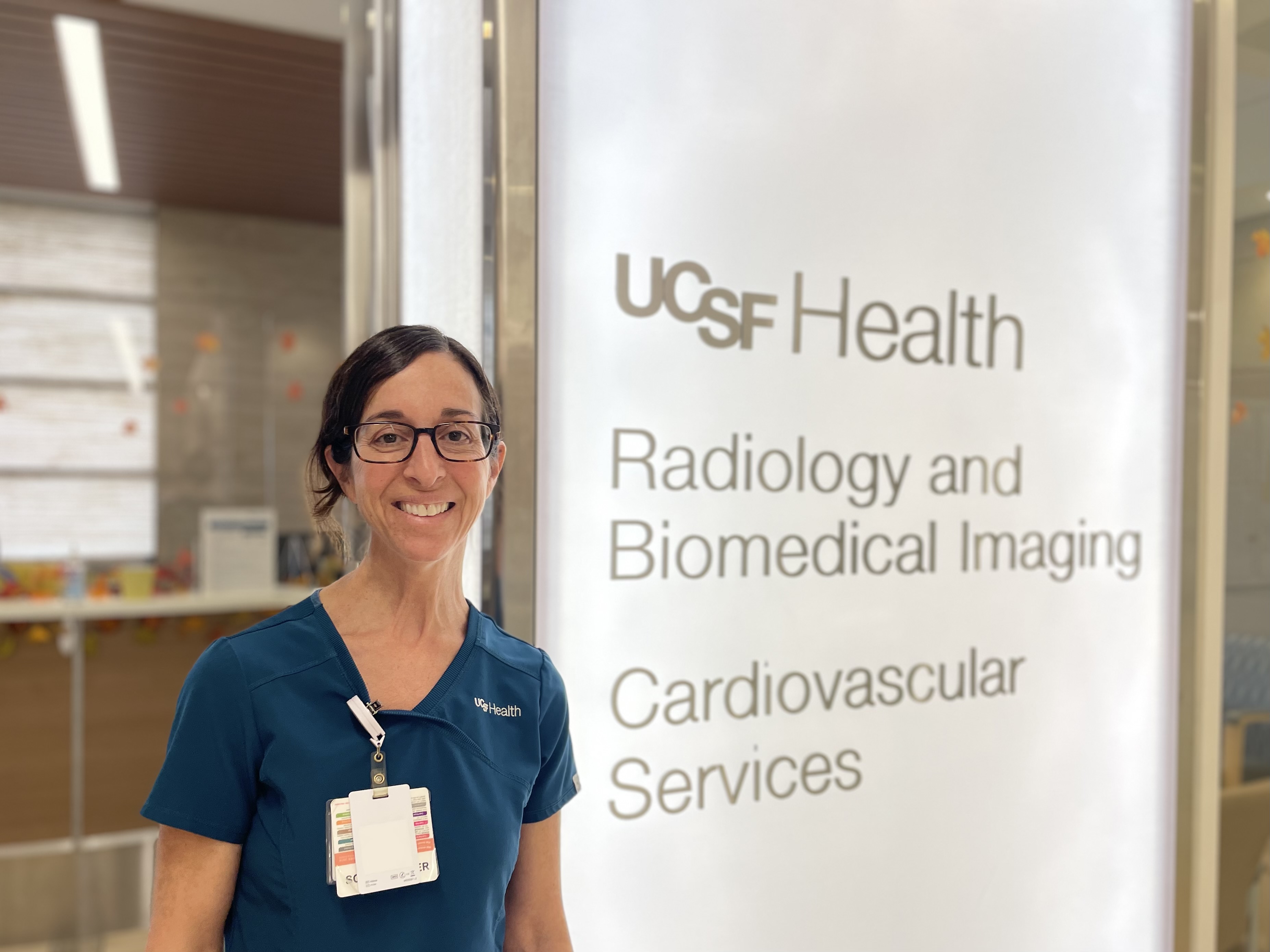 Principal Ultrasound Technologist, Jane Glover, RDMS, RVT, Parnassus Heights. Woman smiling in front of Radiology reception area at UCSF Parnassus Heights