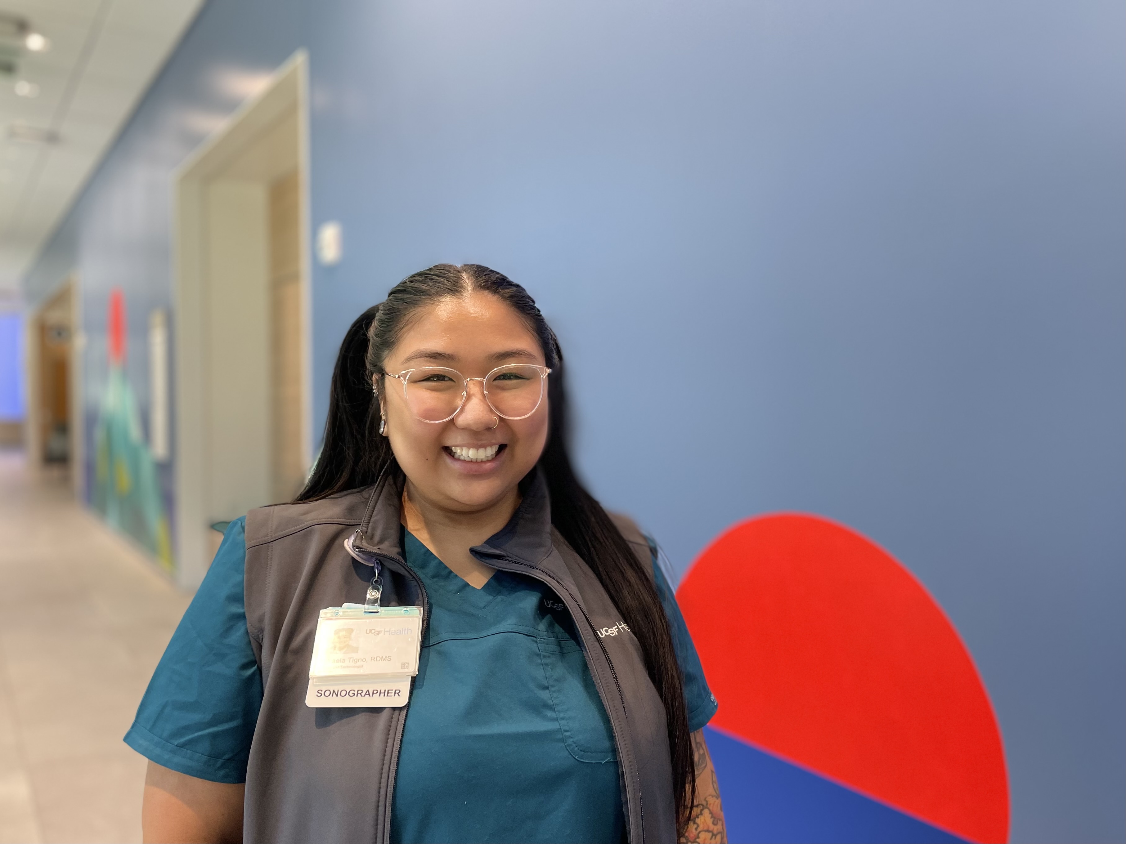 Ultrasound Technologist Mikaela Tigno, RDMS, Bayfront. Woman with glasses smiling at Radiology reception at Bayfront Medical Building.