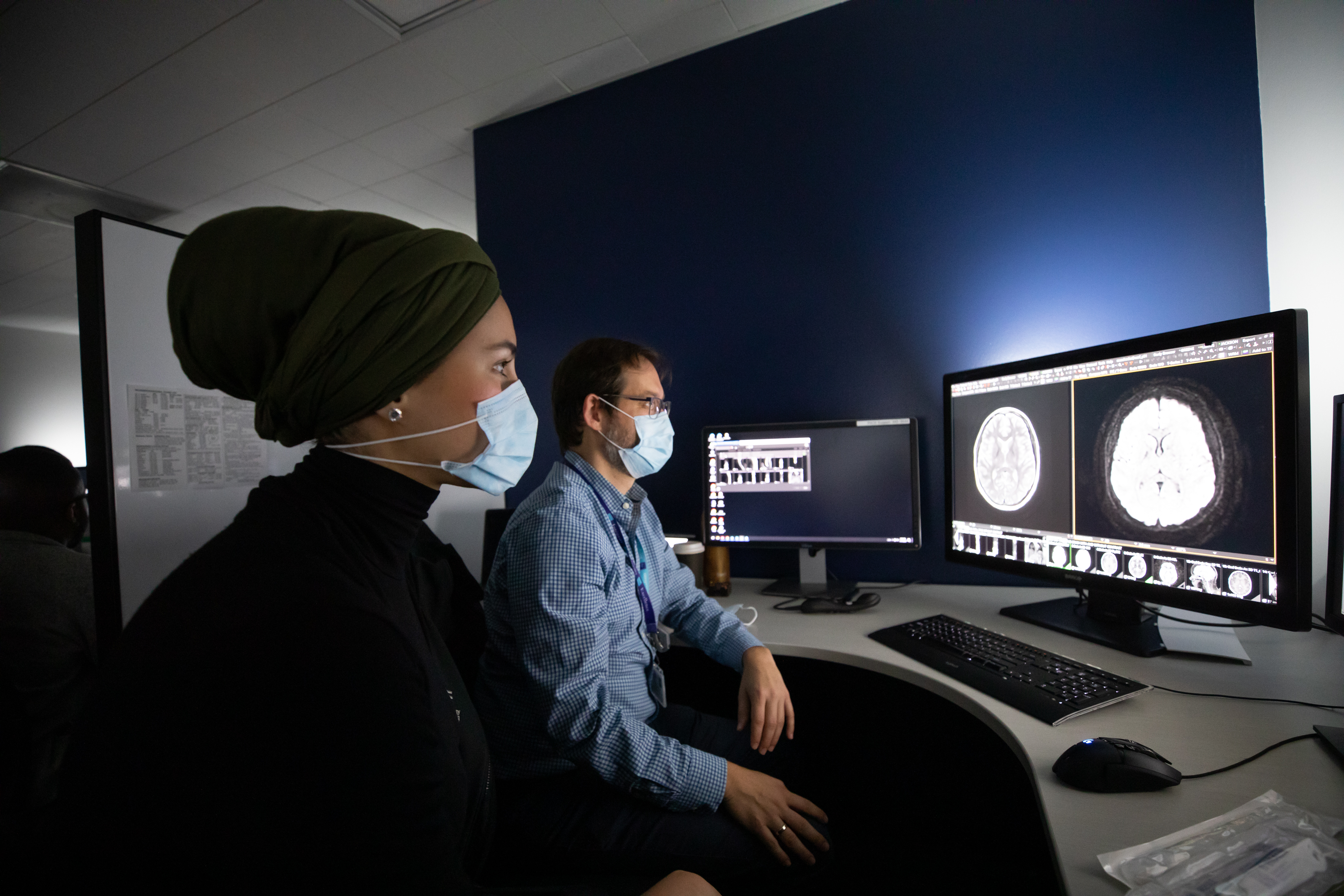 Radiologists looking at a scan on a computer screen in a reading room.