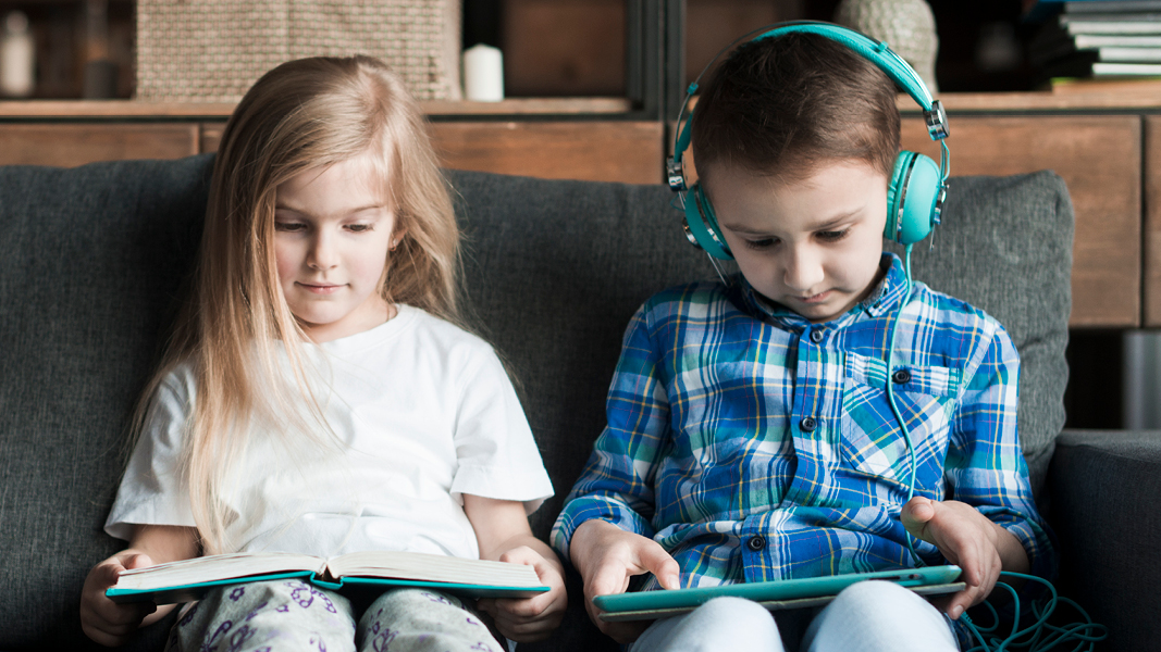 Kids looking at tablet and a book