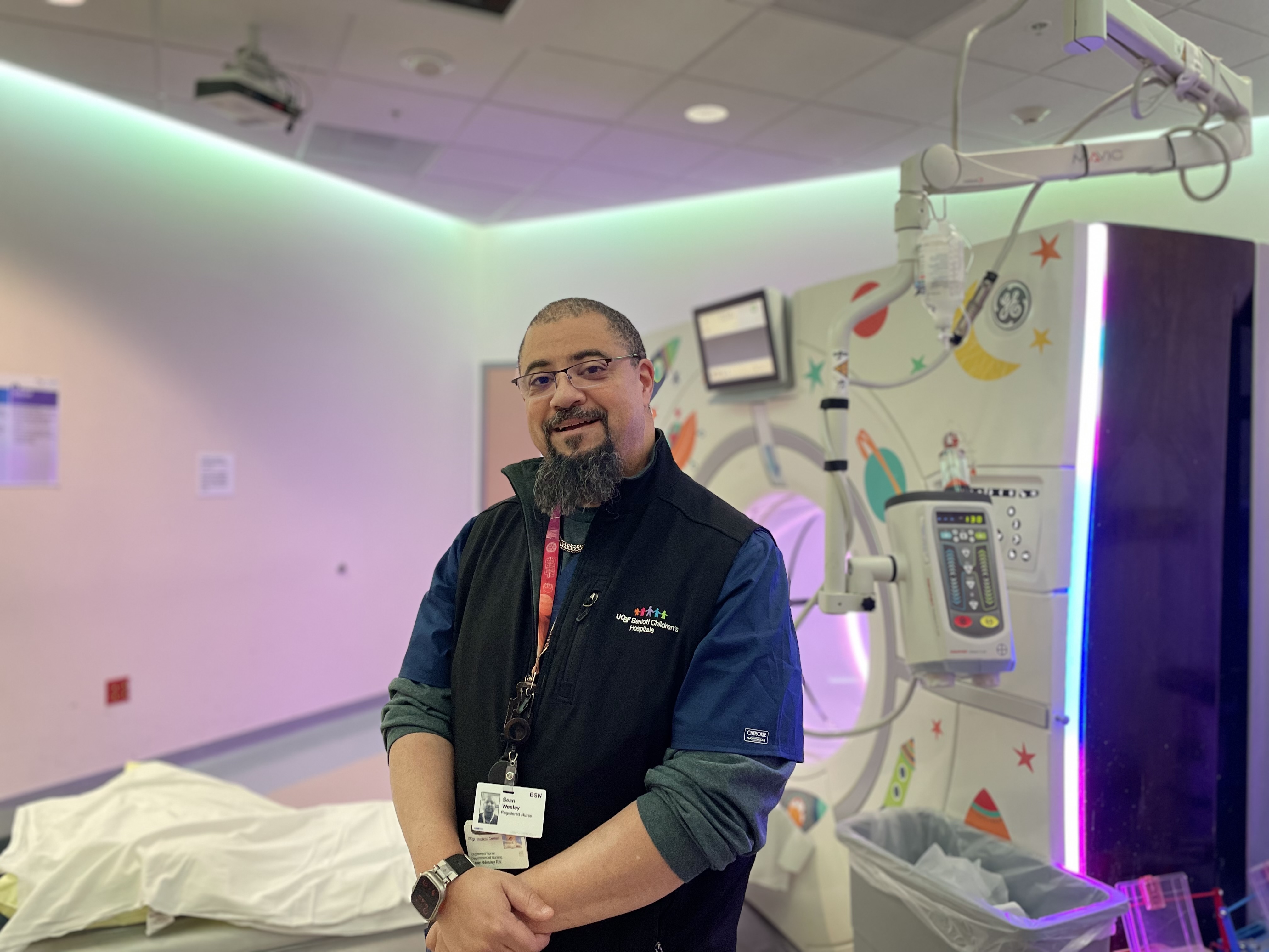Man smiling in front of MRI machine.