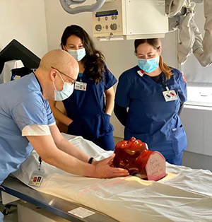 Mount Zion Diagnostic Supervisor Chester Lim teaching skull positioning to CCSF students Raquel Raygoza and Gretel Perez.
