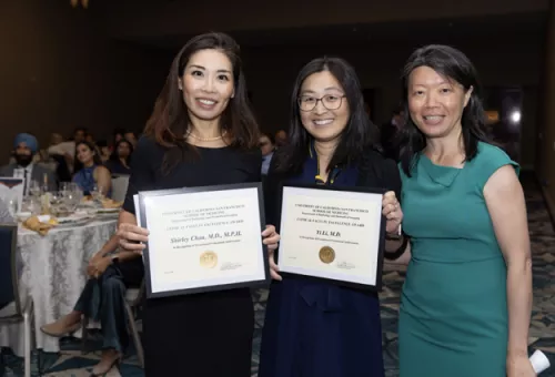 Shirley Chou and Yi Li hold their Clinical Faculty Excellence Award certificates while posing with a colleague at a UCSF Department of Radiology awards ceremony.
