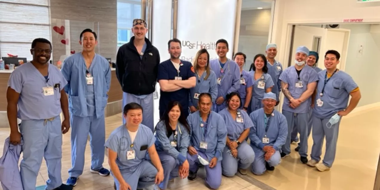 group of radiology staff in scrubs posing together inside a UCSF Health hallway, smiling toward the camera