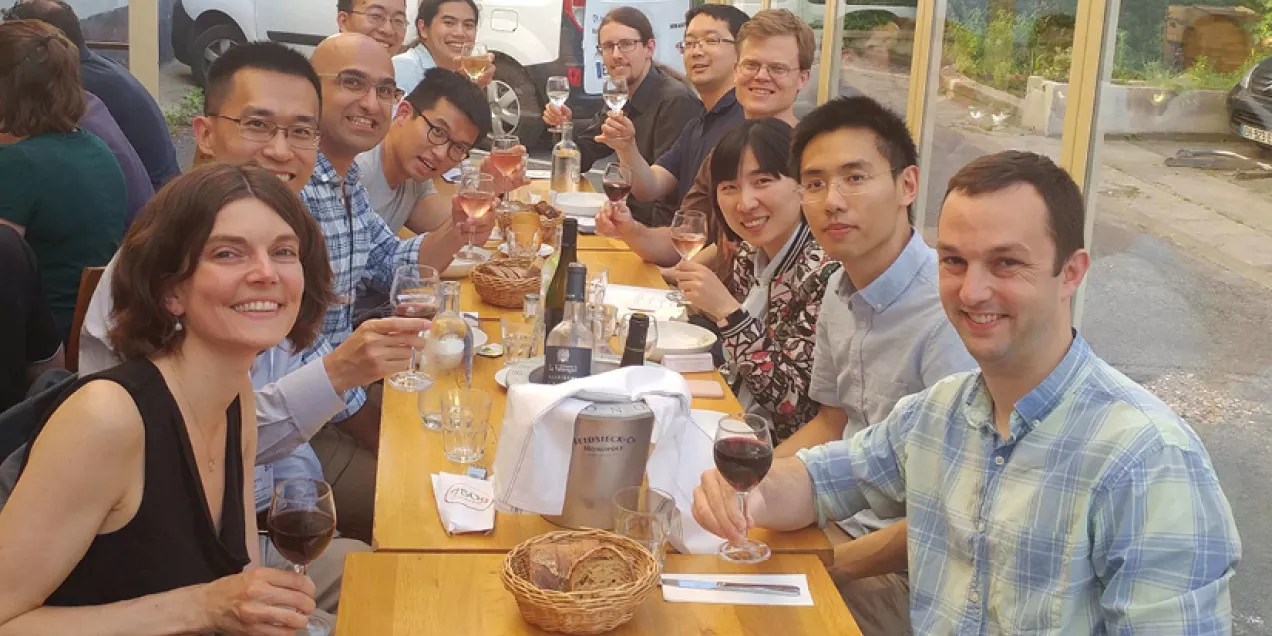 Larson Lab group seated at a long table, smiling and raising glasses at dinner.