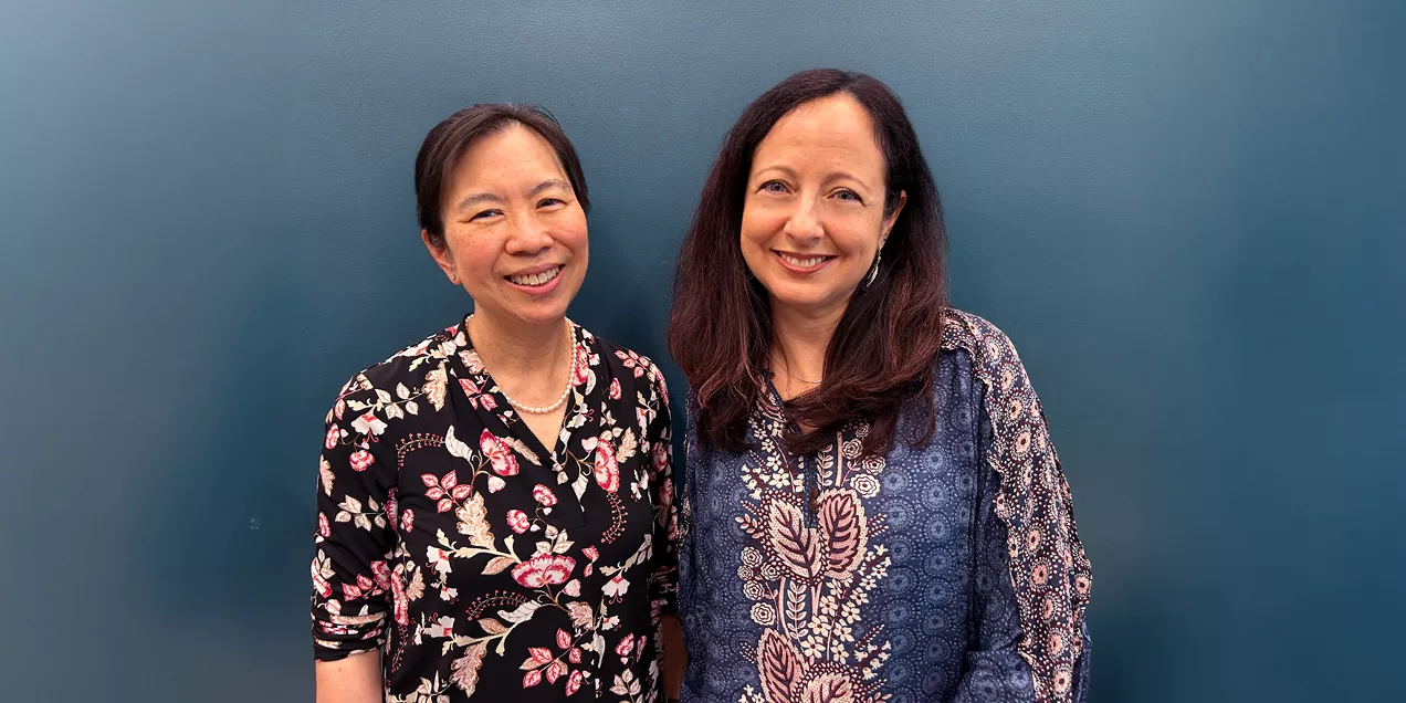 Drs. Joe and Lupo side by side smiling against a teal background, wearing patterned blouses