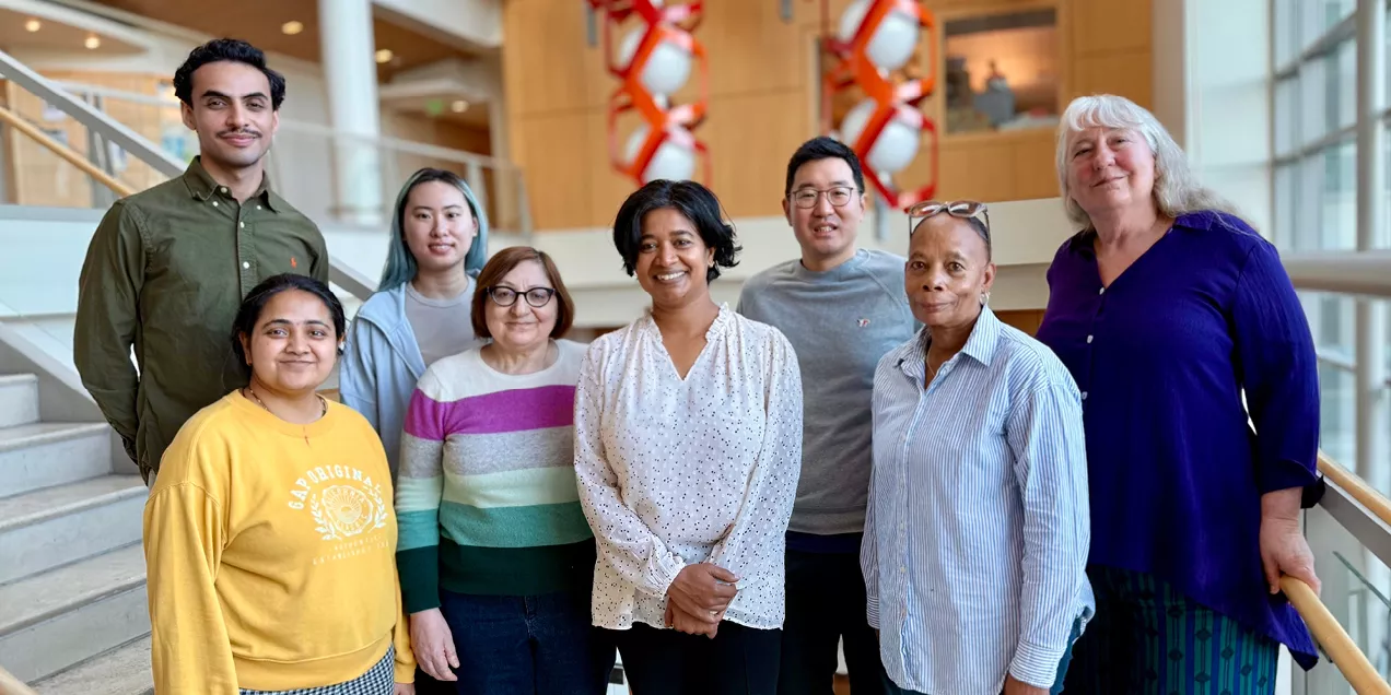 Multidisciplinary research team standing in hospital atrium representing collaboration in precision oncology and imaging