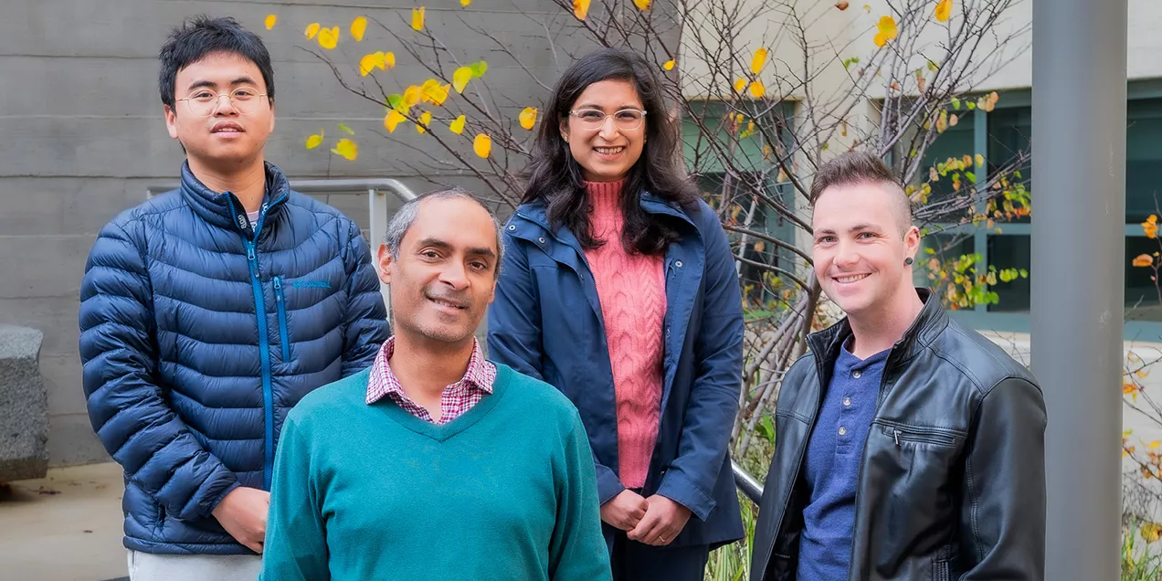 Research team posing together outside near trees with yellow leaves in background