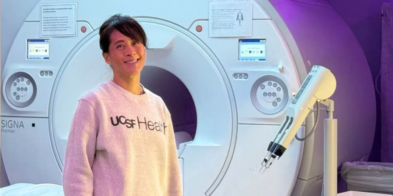 Woman wearing a UCSF Health sweatshirt standing in front of an MRI scanner.