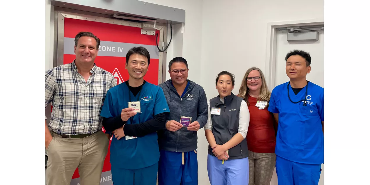 Six healthcare staff members gather near an MRI Zone IV entrance, with two displaying MRI safety treats.