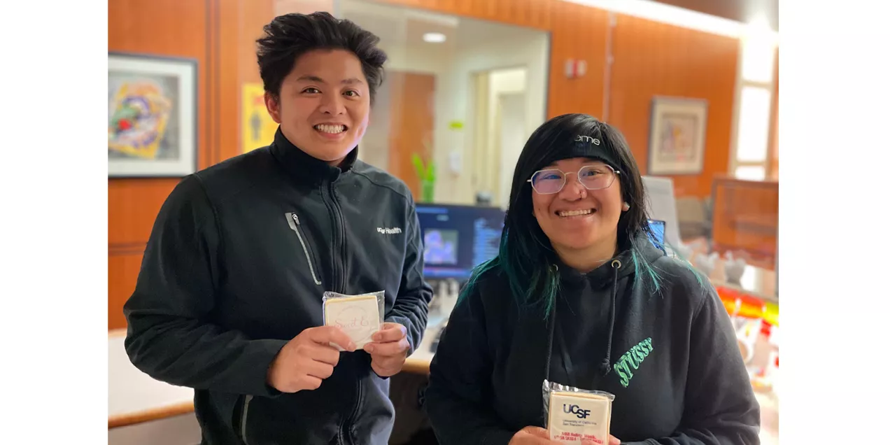 Two staff members pose together in a clinical workspace while holding UCSF MRI Safety Week treats.