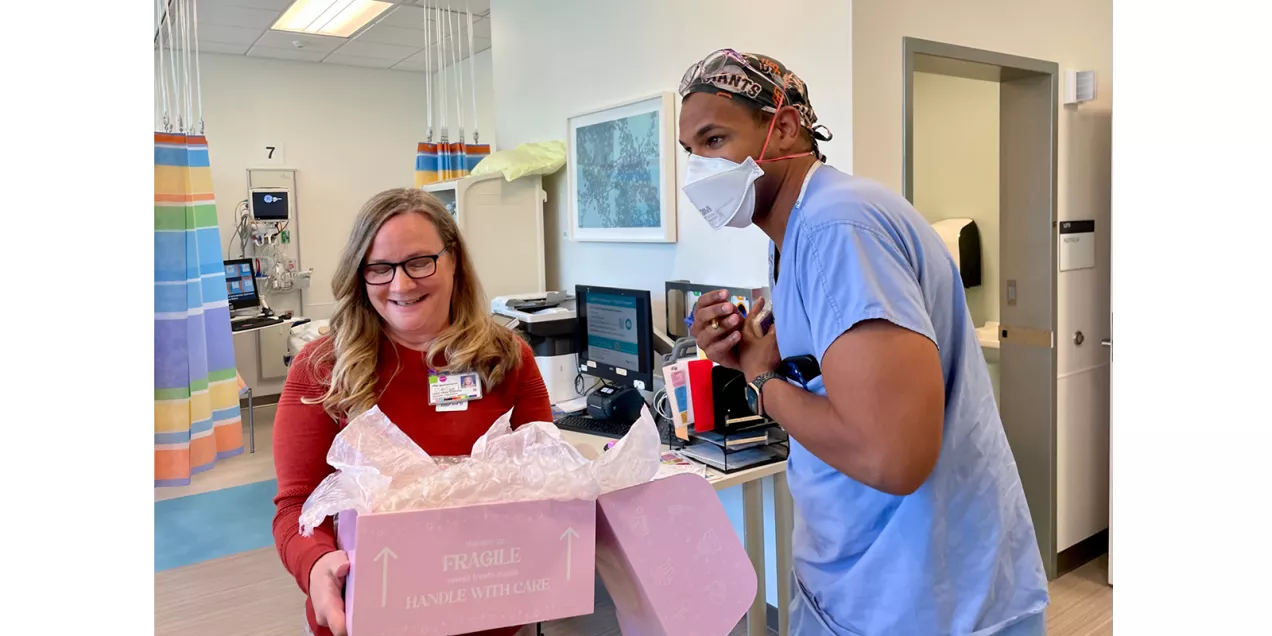 Two healthcare staff members in a clinical area with an open box of MRI Safety Week treats.
