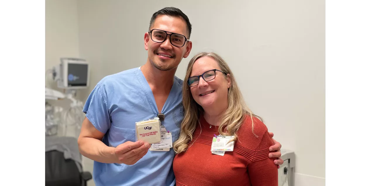 Two healthcare staff members pose together while one holds a UCSF MRI Safety Week cookie.