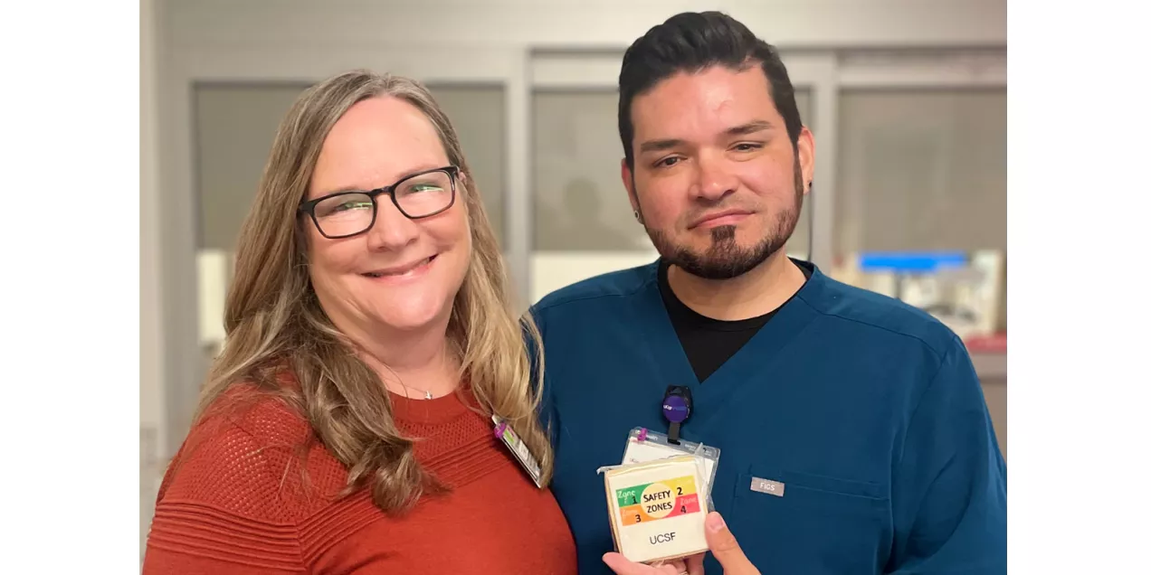 Two staff members pose together in a clinical area while displaying a UCSF MRI safety zones cookie.