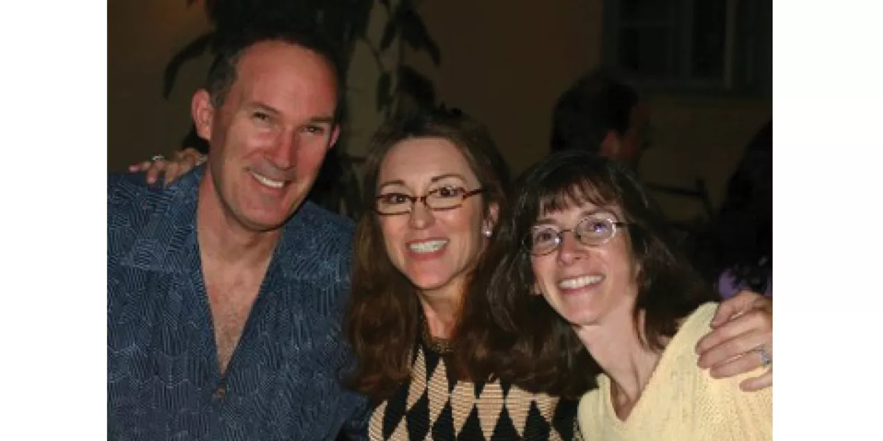 Three people smiling together at a social gathering.