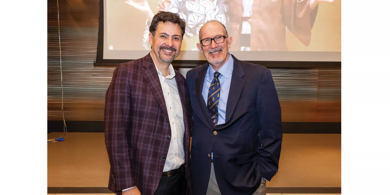 Two men in business attire smiling together at a department event.