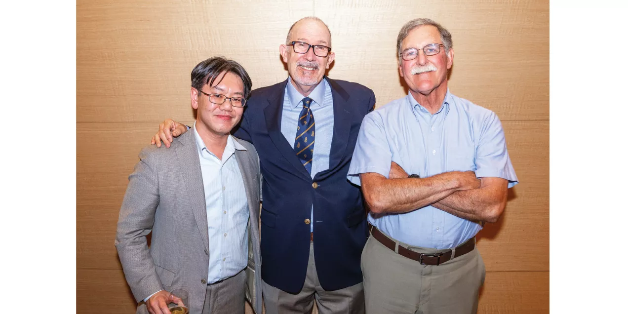 Three men standing together and smiling at a department event.