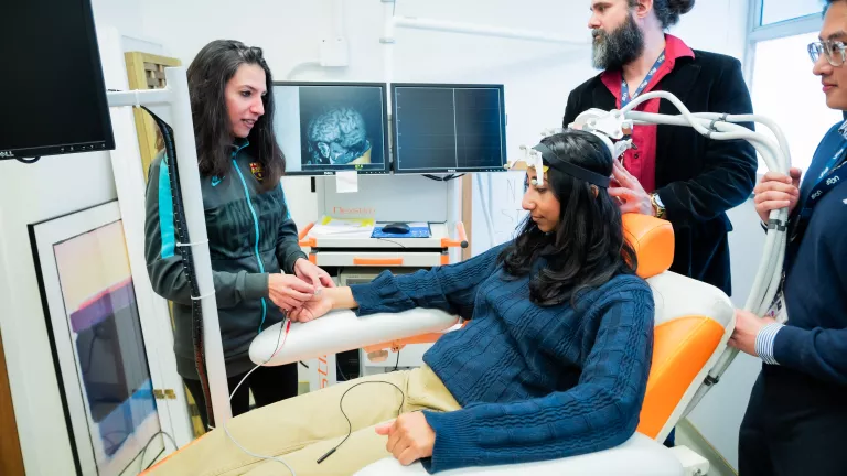 A patient sitting in a chair prepares for a brain imaging exam