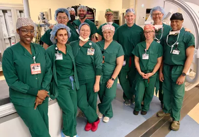 Group of interventional radiology team members in surgical scrubs standing in procedure room