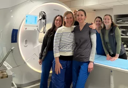Group of clinical staff standing beside an MRI scanner in a hospital imaging room