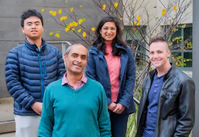 Group of researchers standing outdoors in front of building with autumn leaves