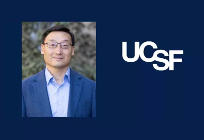 Portrait of a man wearing glasses and a blue blazer over a light blue shirt, standing outdoors with a blurred natural background. On the right side, a dark blue panel displays the UCSF logo in white.
