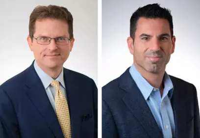 Side-by-side professional headshots of two men in business attire against a light gray background. The man on the left wears glasses, a navy suit, a light blue shirt, and a patterned yellow tie. The man on the right wears a blue blazer and light blue shirt without a tie. Both are facing the camera with neutral, professional expressions.