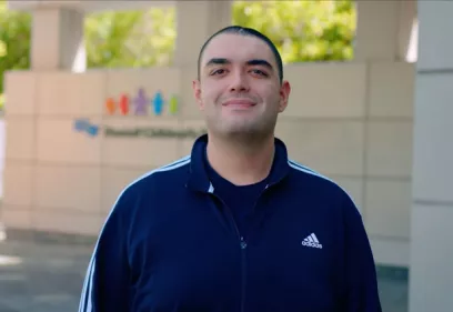 Andrew Santos smiles as she stands in front of U C S F Benioff Children's Hospital, San Francisco.