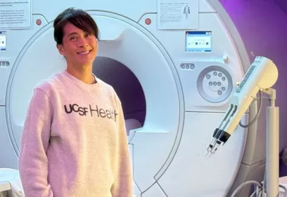 Woman wearing a UCSF Health sweatshirt standing in front of an MRI scanner.