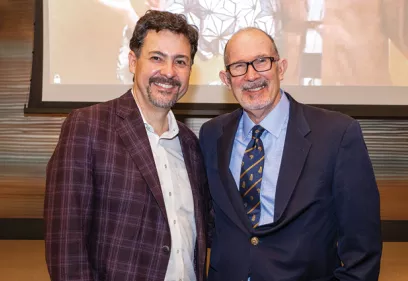 Two men in business attire smiling together at a department event.