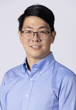 Portrait of Frederick Moh, MD smiling, wearing glasses and a light blue button-down shirt against a light gray background.