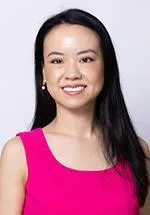 Portrait of a smiling woman with long dark hair wearing a bright pink sleeveless top.