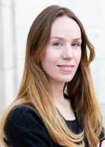 Head and shoulders portrait of a woman with long hair smiling outdoors
