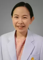 Professional headshot of Tunlada, a smiling woman with dark hair pulled back wearing a white coat and patterned blouse against a gray background.