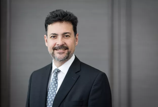 Chair, Christopher Hess headshot of a clinician wearing a suit and tie, smiling toward the camera against a neutral background.
