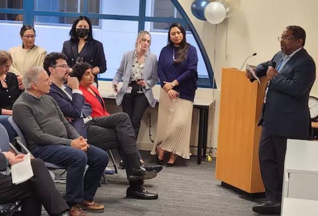 Attendees listen as a speaker addresses the audience from a podium during a UCSF event.