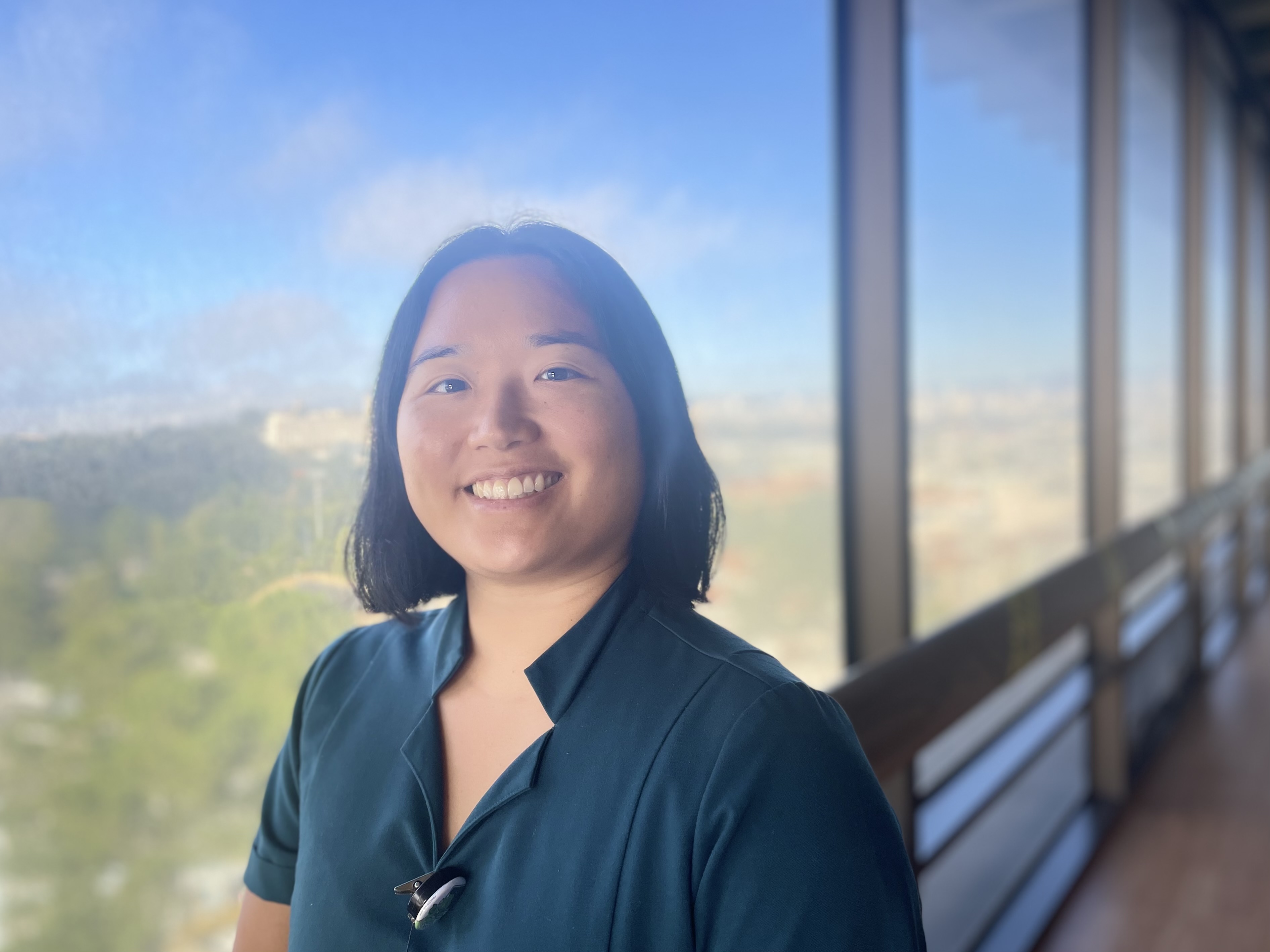 Woman smiling in front of a window at UCSF 400 Parnassus medical building.