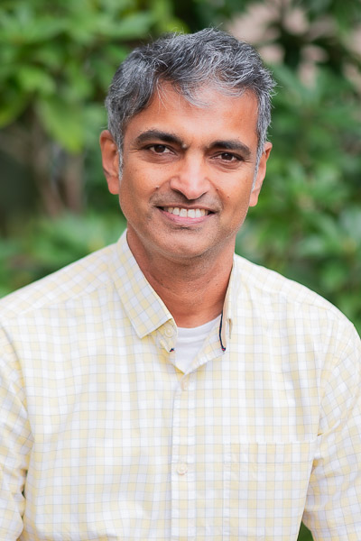 Man in light shirt in front of green leaves